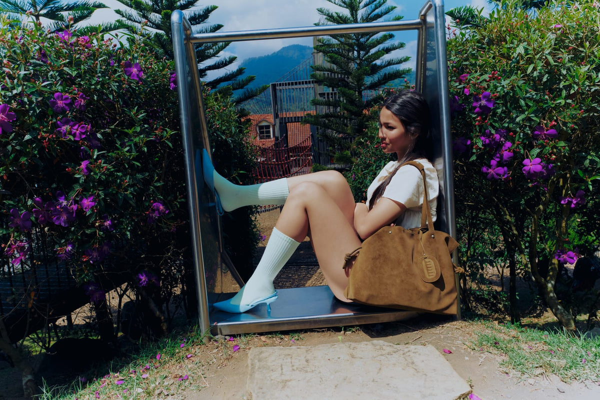 Isabelle Bag in Earth — sitting in a slide among purple flowers