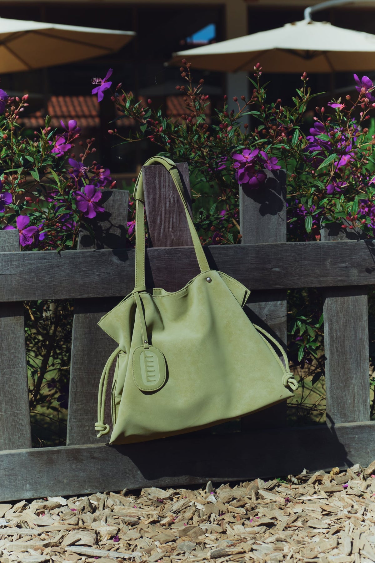 Isabelle Bag in Meadow — hanging on a garden fence