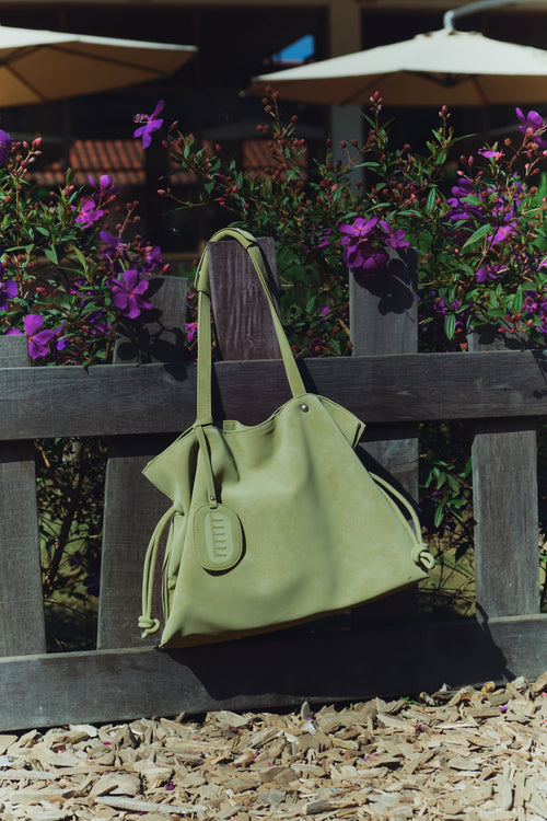 Isabelle Bag in Meadow — hanging on a garden fence