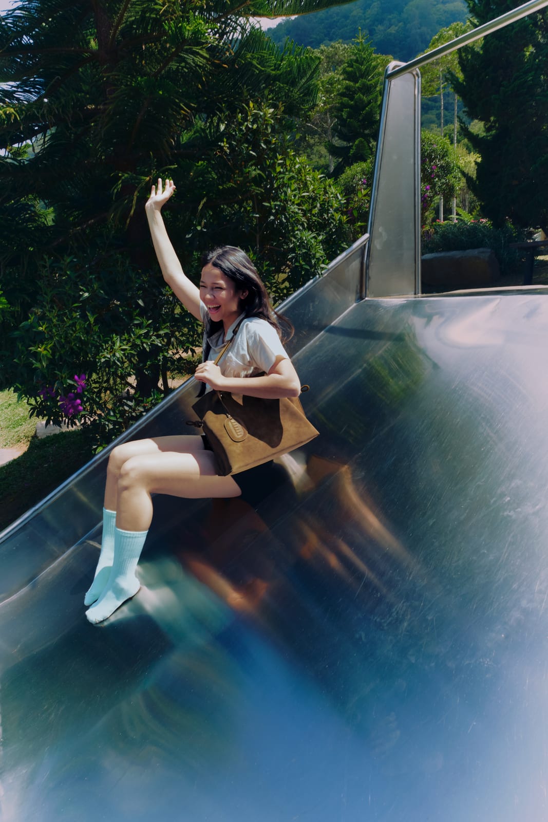 Isabelle Bag in Earth — campaign, waving from a slide