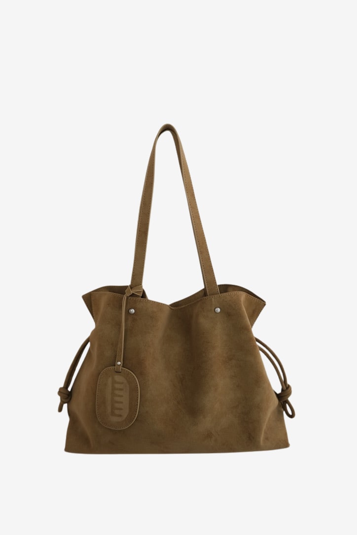 Isabelle Bag in Earth — front with the bag charm, on light grey