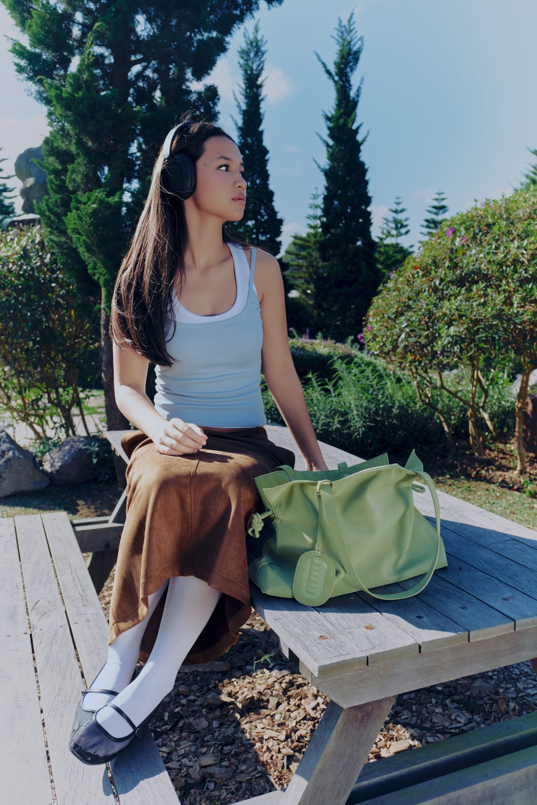 Isabelle Bag in Meadow — campaign, sitting on a garden bench