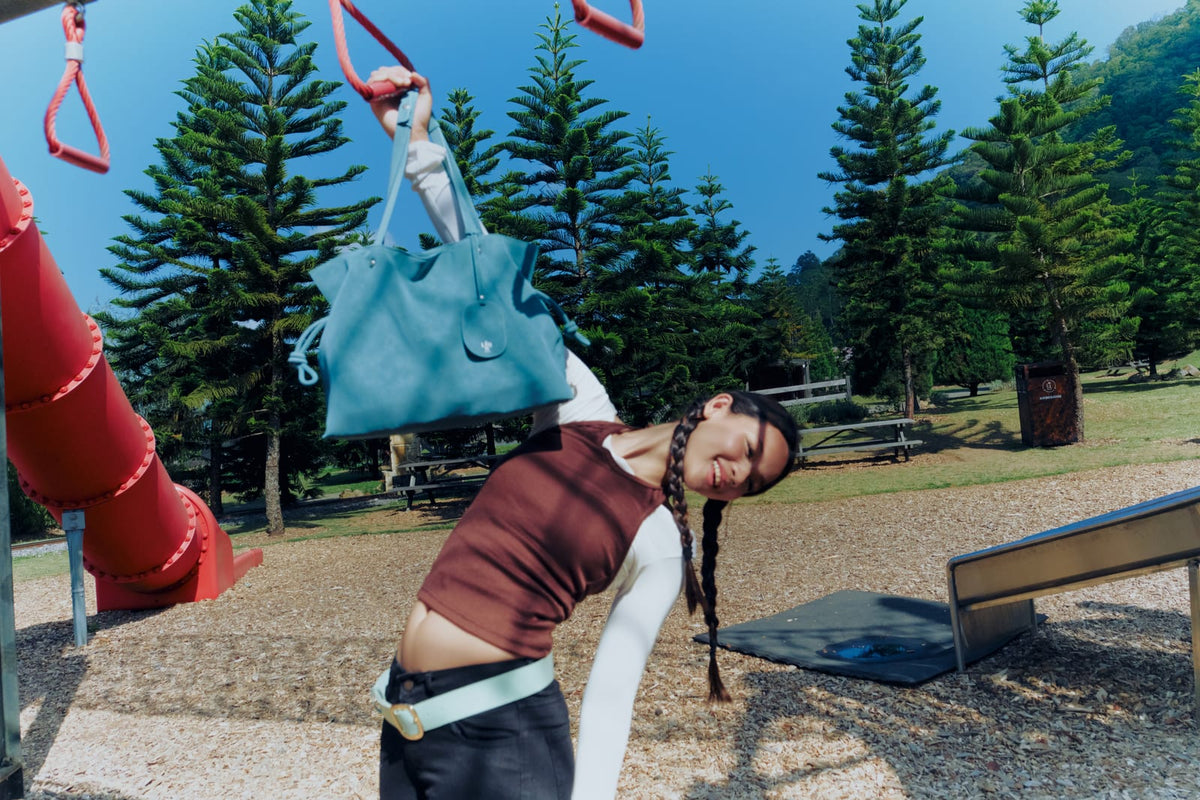 Isabelle Bag in Sky — campaign, swinging from the monkey bars