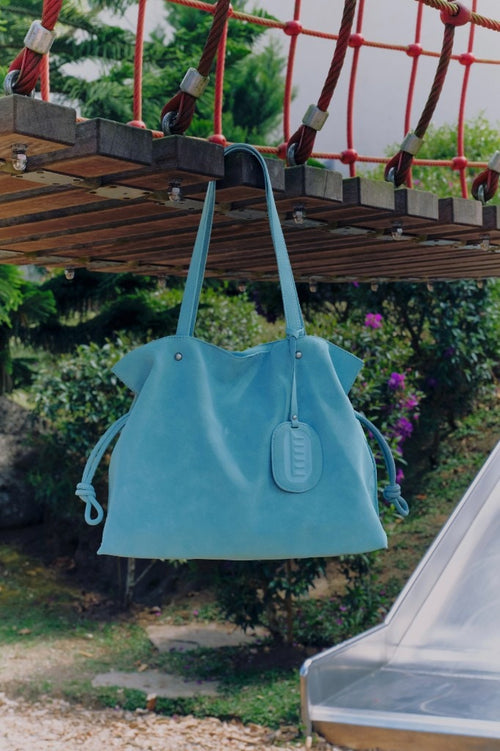 Isabelle Bag in Sky — hanging under a rope bridge