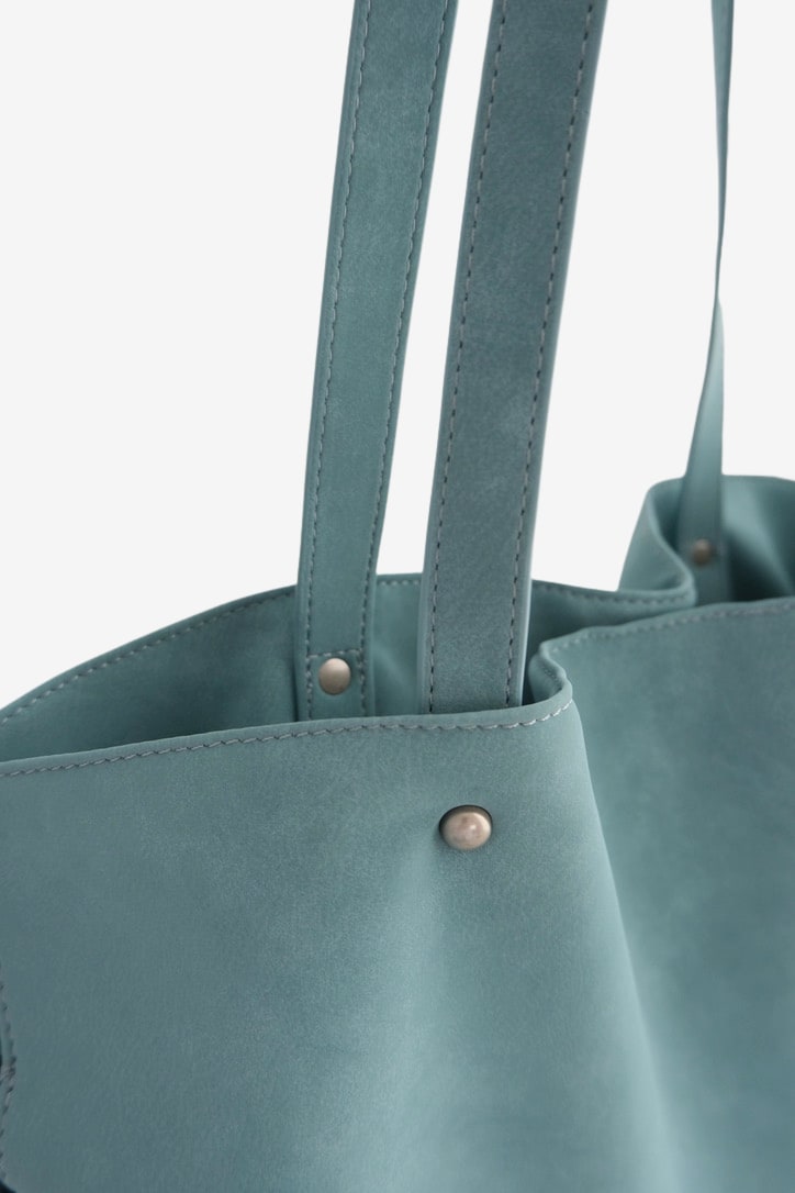 Isabelle Bag in Sky — strap and rivet close-up, on light grey